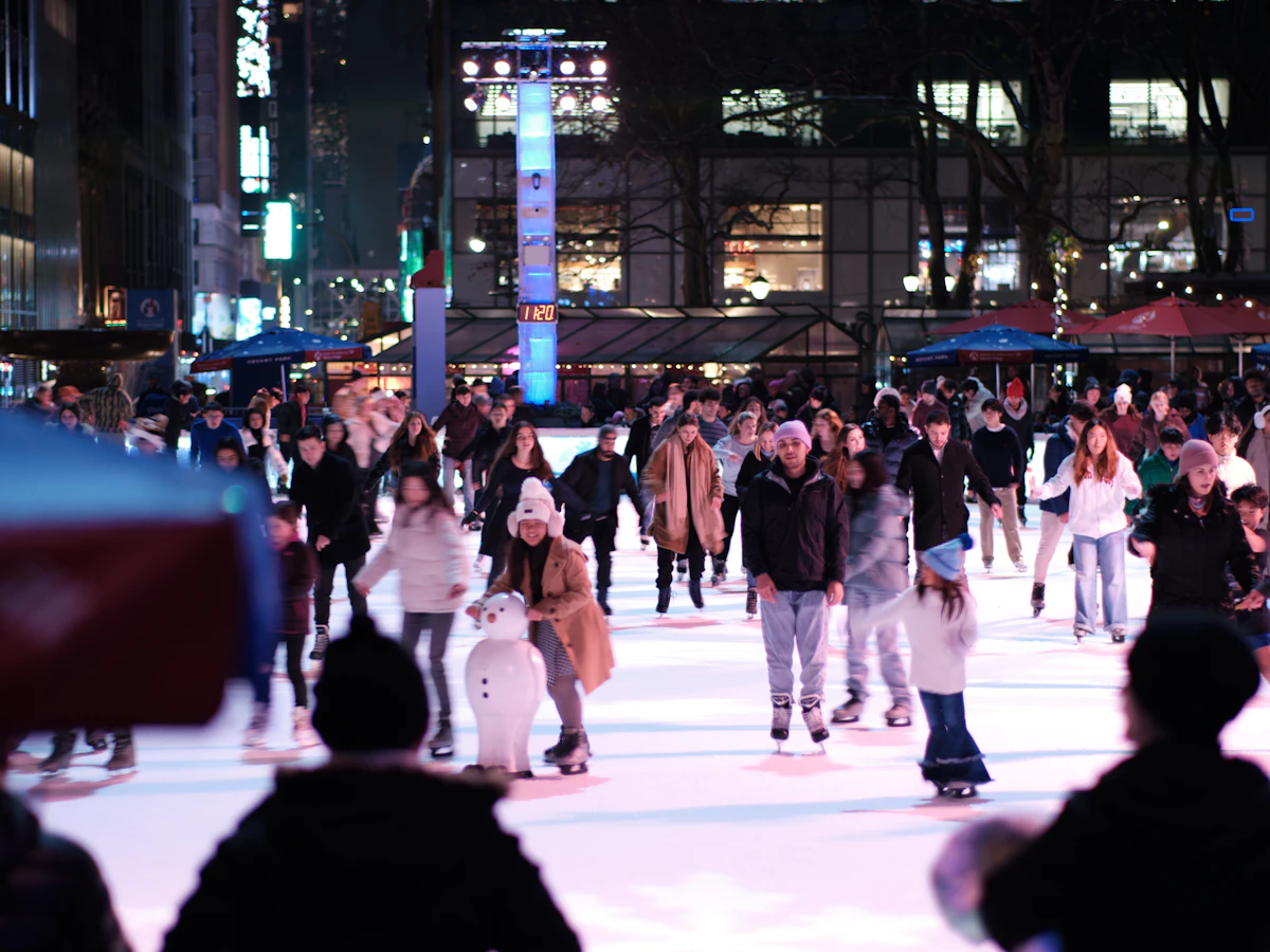 A crowded outdoor ice rink lit up at night in the city