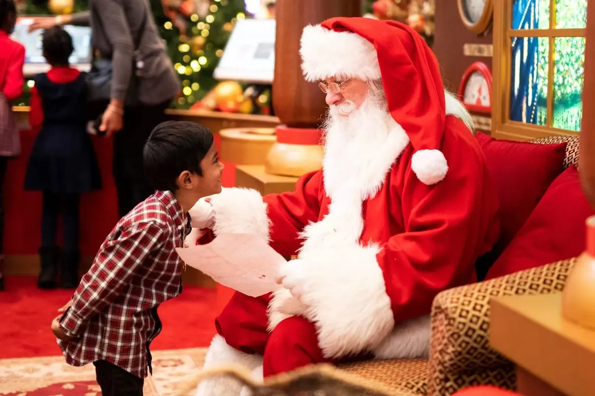 A child meeting Santa Claus beside a decorated Christmas tree